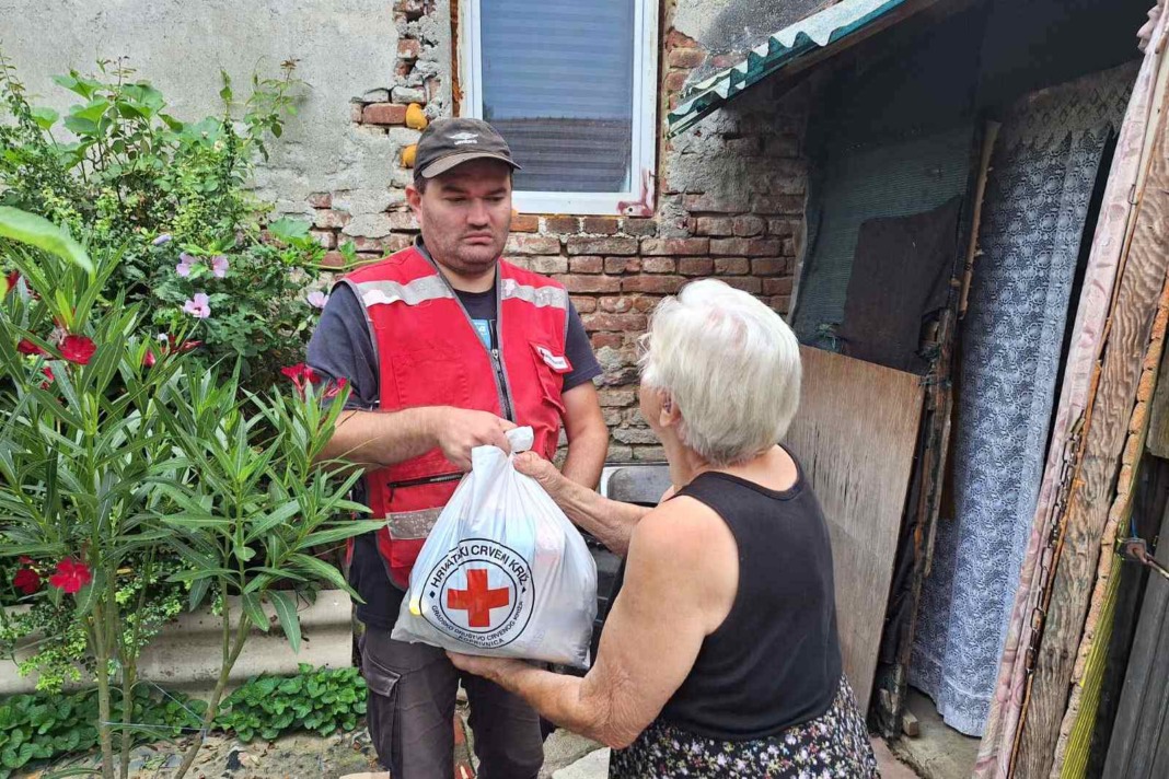 Volonter Crvenog križa predaje paket proizvoda starijoj gospođi